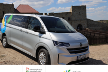 mikrobus do przewozu osób z niepełnosprawnością oklejony logo Dobczyc stoi na ścieżce, w tle widać dobczycki zamek