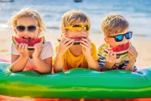 Troje dzieci jedzących arbuzy na plaży