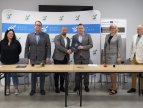 przy stole stoją przedstawiciele wykonawcy oraz burmistrz Tomasz Suś, skarbnik Antonia Trojan, specjalista ds. polityki społecznej Marek Gabzdyl i pracownik Referatu Inwestycji Katarzyna Borczak, podczas podpisania umowy