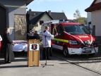 na placu przed remizą OSP w Stadnikach stoi lekki samochód ratowniczo-gaśniczy, z lewej strony samochodu stoi ksiądz i święci nowy nabytek, w centrum zdjęcia widać mównicę i mikrofon, z tyłu za mównicą stoi stół z białym obrusem na którym ustawione są statuetki
