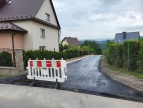 Świeży aswalt wylany na drodze w Brzezowej. Na drodze zastawiona jest  barierka w kolorze białym z czerwonym aby nie wjeżdzać 