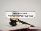 Na zdjęciu widoczna jest otwarta księga, na której spoczywa drewniany młotek sądowy. Na środku grafiki znajduje się jasny prostokąt w ozdobnej ramce, zawierający napis: Obwieszczenie Wojewody Małopolskiego
