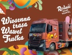 Kolorowa grafika promująca Wiosenną Trasę Wawel Trucka. Na ilustracji czerwony samochód ciężarowy marki Wawel na brązowym tle z dekoracyjnymi, wiosennymi motywami.