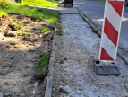 widok jezdni wzdłuż ulicy Jałowcowej oraz chodnika z z którego rozebrano nawierzchnię, w miejscu chodnika ustawione znaki ostrzegające o braku przejścia
