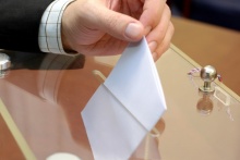 dłoń wrzucająca kartę do głosowania do urny