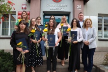 zdjęcie grupowe, przed wejściem do Urzędu Gminy stoją nauczycielki które otrzymały tytuł nauczyciela mianowanego oraz burmistrz Tomasz Suś wraz z zastępcą Edytą Podmokły