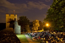 Zdjęcie z pełną widownią ludzi, uczestniczących na zamku w Dobczycach podczas kina plenerowego.