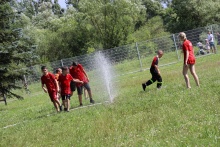 Chłopcy bawiący się w parku miejskim przy strumieniu z wody. Dzieci ubrani są w czerwone koszulki