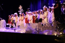 grupa małych dzieci w białych ubraniach występują na dużej scenie 