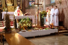 Święto plonów - czas wdzięczności i współnego spotkania Msza dożynkowa w kościele, przy ołtarzu proboszcz i ministranci, przed nimi wieńce i dary dożynkowe.