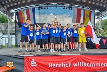 Grupa chłopców z trenerem piłki nożnej w niebieskich koszulkach cieszący się z wygranego meczu