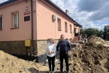 budynek szkoły, przed nim ziemi chałdy, na pierwszym planie burmistrz Tomasz Suś i wiceburmistrz Edyta Podmokły