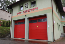 budynek OSP Brzezowa od frontu z 2 szt drzwi garażowych w kolorze czerwonym nad drzwiami napis OSP Brzezowa 