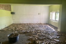 Remontowane pomieszczenie w szkole podstawowej w Dobczycach, ściany pomieszczenia są zielone. Na podłodze rozwalone są kawałki drewna po modernizacji