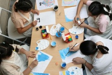 Kilkoro dzieci na zajęciach plastycznych malujących farbami