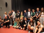 raper Roman Bosski pod sceną w auli widowiskowej pozuje z młodzieżą do zdjęcia