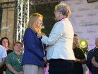 Wicewojewoda Elżbieta Achinger przypina Edycie Podmokły Odznakę Honorową za Zasługi dla Samorządu Terytorialnego podczas uroczystości wręczenia odznaczeń w czasie Dni Dobczyc. W tle widoczni są uczestnicy wydarzenia.