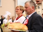 Dwójka ludzi trzymająca dar -chleb ,niesiony do kościoła 