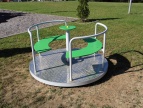 okrągłe metalowe urządzenie na placu zabaw z zielonymi deskami 