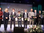 Na scenie podczas uroczystej gali stoją w rzędzie laureaci wyróżnienia burmistrza w dziedzinie sportu, każdy z nich trzyma statuetkę i różę,  wraz z przedstawicielami samorządu 