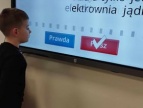 chłopiec stoi przed interaktywną tablicą na której wyświetlone jest pytanie i odpowiedzi: prawda, fałsz