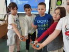 dzieci stoją w póokręgu dłonie mają skierowane w środek okręgu w rękach trzymają ulepione z plasteliny kule ziemskie