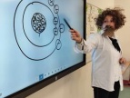 Ignacy stoi przy tablicy interaktywnej, na której wyświetlany jest jakiś model, Ignacy wskazuje długopisem na punkt tablicy