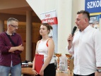 Pan Burmistrz ubrany w białą koszulę przemawia do przybyłych gości przez czarny mikrofon. Tuż obok stoi kobieta z mężczyzną 