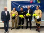 zdjęcie trzech druhów OSP z hełmami w rękach wspólnie z burmistrzem Tomaszem Susiem i pracownikiem urzędu Andrzejem Panusiem