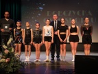 Na scenie podczas uroczystej gali stoją członkowie sekcji gimanstyki sportowej z burmistrzem i trenerem