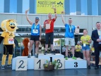 Trzech uczestników stojący na podium. Uczestnicy cieszą się z osiągniętych wyników 