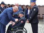 Dwóch mężczyzn wręczający oznakę panu na wózku inwalidzkim 