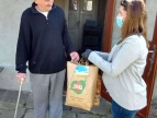 Pracownicy socjalni przekazuja paczki żywnościowe seniorom