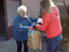 Pracownicy socjalni przekazuja paczki żywnościowe seniorom