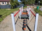 metalowe poręcze umocowane na placu zabaw. rurki tego urządzenia mają kolor czerwoy bądź szary 