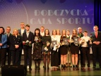 na scenie stoją w dwóch rzędach przedstawiciele samorządu wraz z laureatami Nagrody Burmistrza w dziedzinie sportu