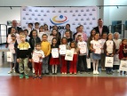 Wręczenie nagród w konkursie plastycznym "Strażacy w akcji - superbohaterowie w hełmach" Grupa dzieci z burmistrzem Tomaszem Susiem oraz dyrektorem MGOKiS Andrzejem Topą z dyplomami i nagrodami podczas uroczystości w MGOKiS Dobczyce.