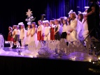 grupa małych dzieci w białych ubraniach występują na dużej scenie 