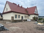 żółty dom ludowy z czerwonym dachem w trakcie modernizacji