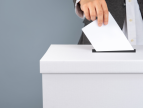 grafika poglądowa dłoń wrzuca kartkę do urny wyborczej