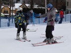 dwójka dzieci jeżdżąca na nartach