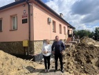 budynek szkoły, przed nim ziemi chałdy, na pierwszym planie burmistrz Tomasz Suś i wiceburmistrz Edyta Podmokły