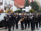 grupa ludzi grający na instrumentach dętych ulicą miasta