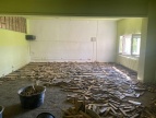 Remontowane pomieszczenie w szkole podstawowej w Dobczycach, ściany pomieszczenia są zielone. Na podłodze rozwalone są kawałki drewna po modernizacji