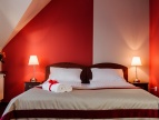 duże łóżko, sciana jest w kolorze czerwonym