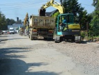 Przebudowa drogi- na zdjęciu żółta duża koparka, a tuż przed nią duży tir z naczepą
