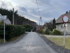 Zdjęcie drogi na Brzezowej. Z lewej strony stoi znak pionowy, biały a po drugiej stronie okrągły