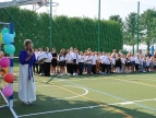 boisko szkolne zielone, rozpoczęcie roku szkolnego 2024/2025, nauczycielka z mikrofonem i grupa uczniów w galowych strojach