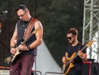 Dwóch mężczyzn grający na gitarach basowych podczas koncertu 