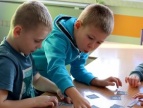 dwójka małych chłopców siedzący przy ławkach szkolnych